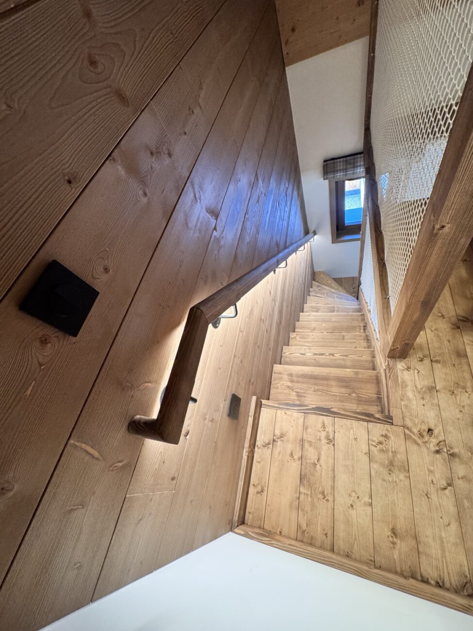 Vue de l’escalier en sapin depuis la mezzanine avec éclairage LED sous la main courante