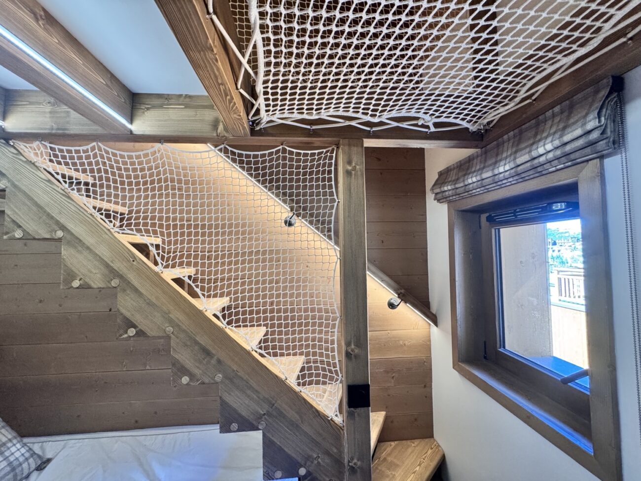 Escalier en sapin avec filet blanc et éclairage intégré dans une chambre à l’Alpe d’Huez