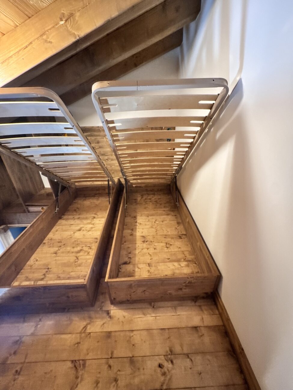 Deux lits coffres sur la mezzanine, avec sommiers relevés et espaces de rangement ouverts